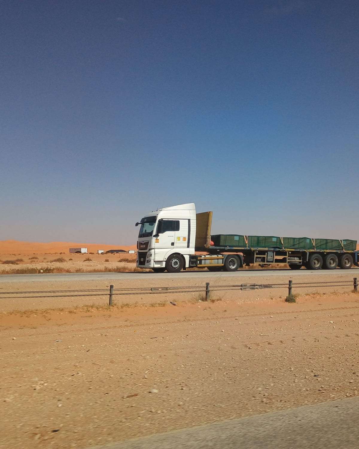 شاحنة نقل تسير على طريق سريع وسط الصحراء تحت سماء صافية